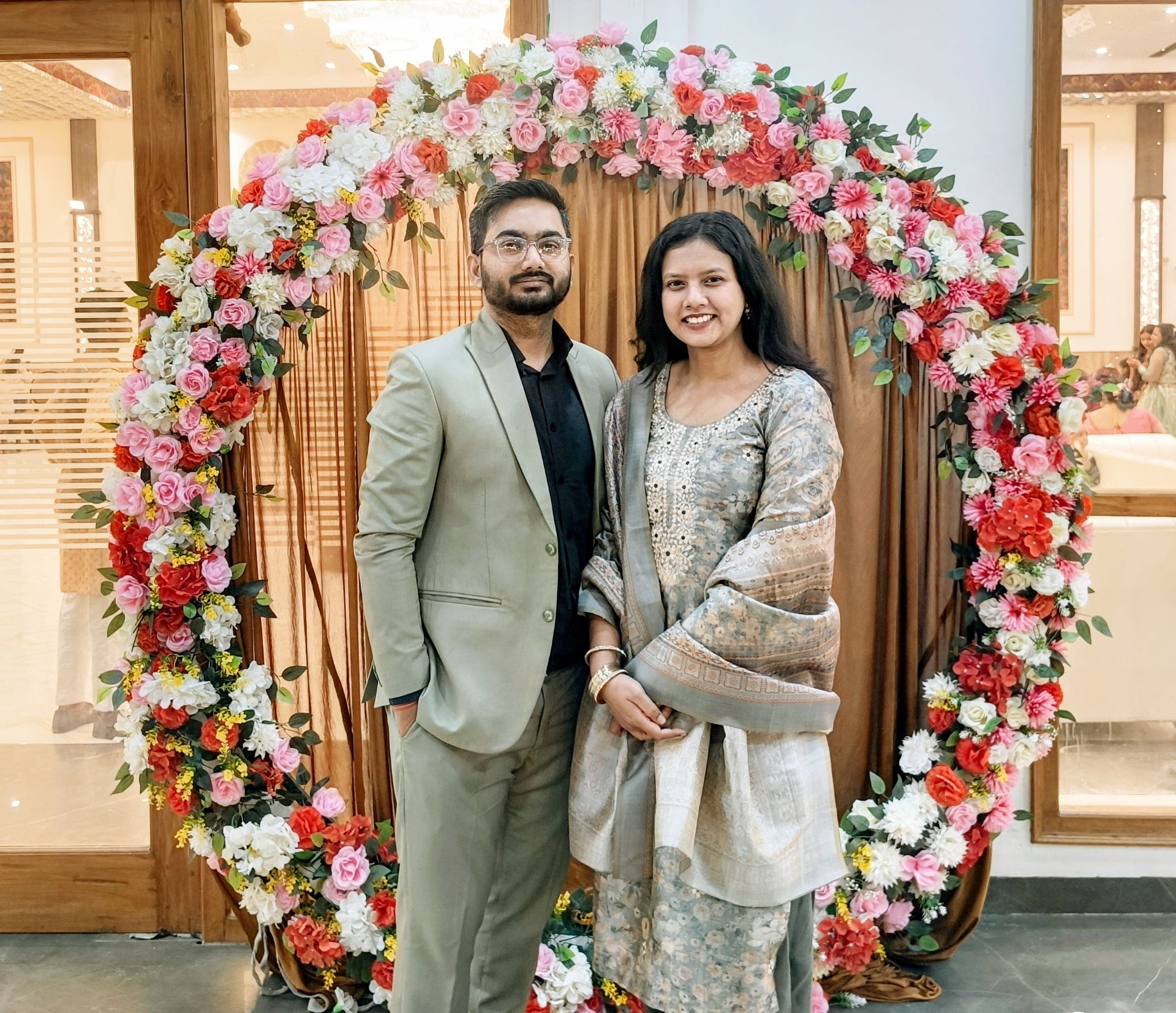Chetan and Jasmine under a floral arch