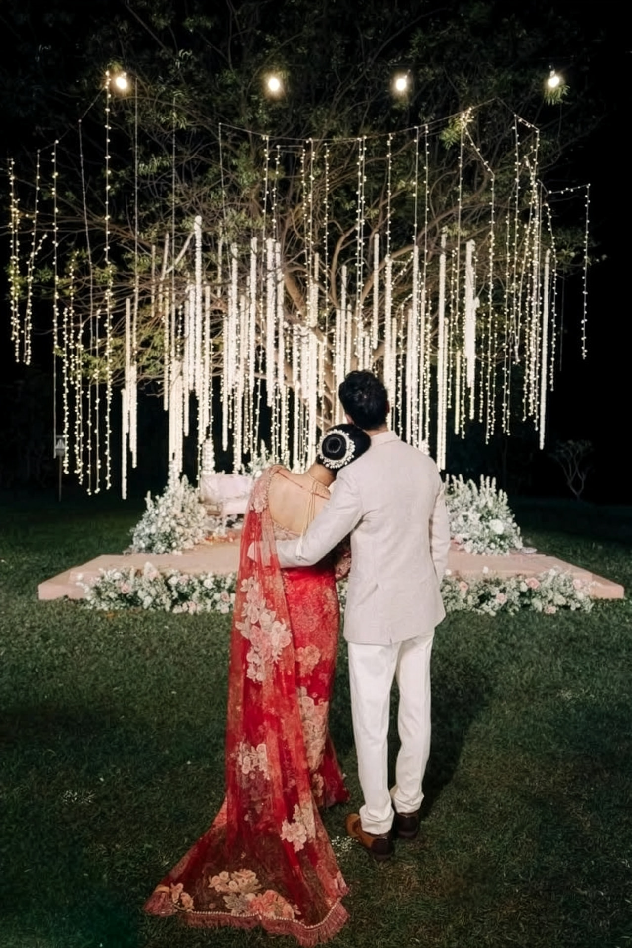 Jasmine and Chetan beneath a canopy of fairy lights and hanging florals